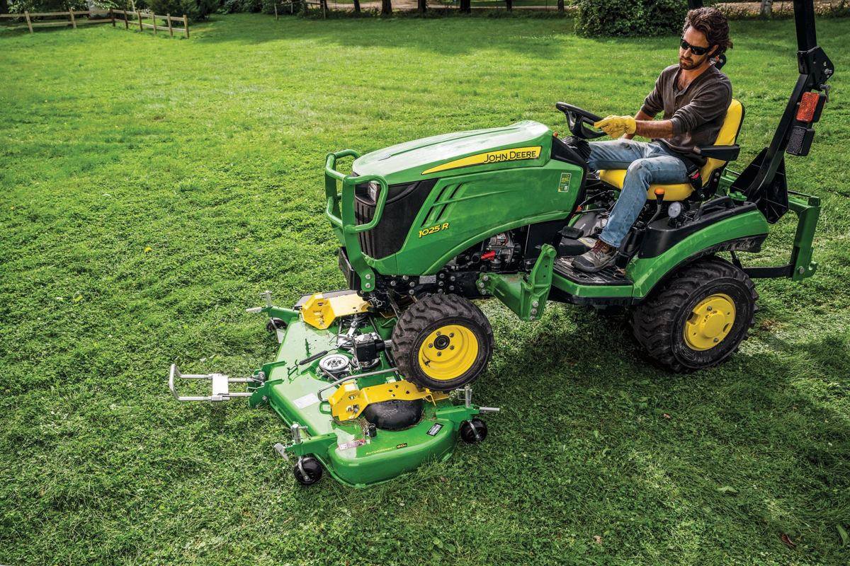 Homeowner mowing a lawn with a John Deere 1025R compact utility tractor and mid-mount mower deck