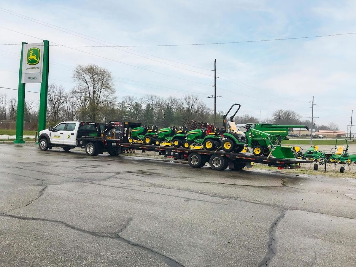 Koenig Equipment pickup towing a trailer loaded with John Deere compact utility tractors