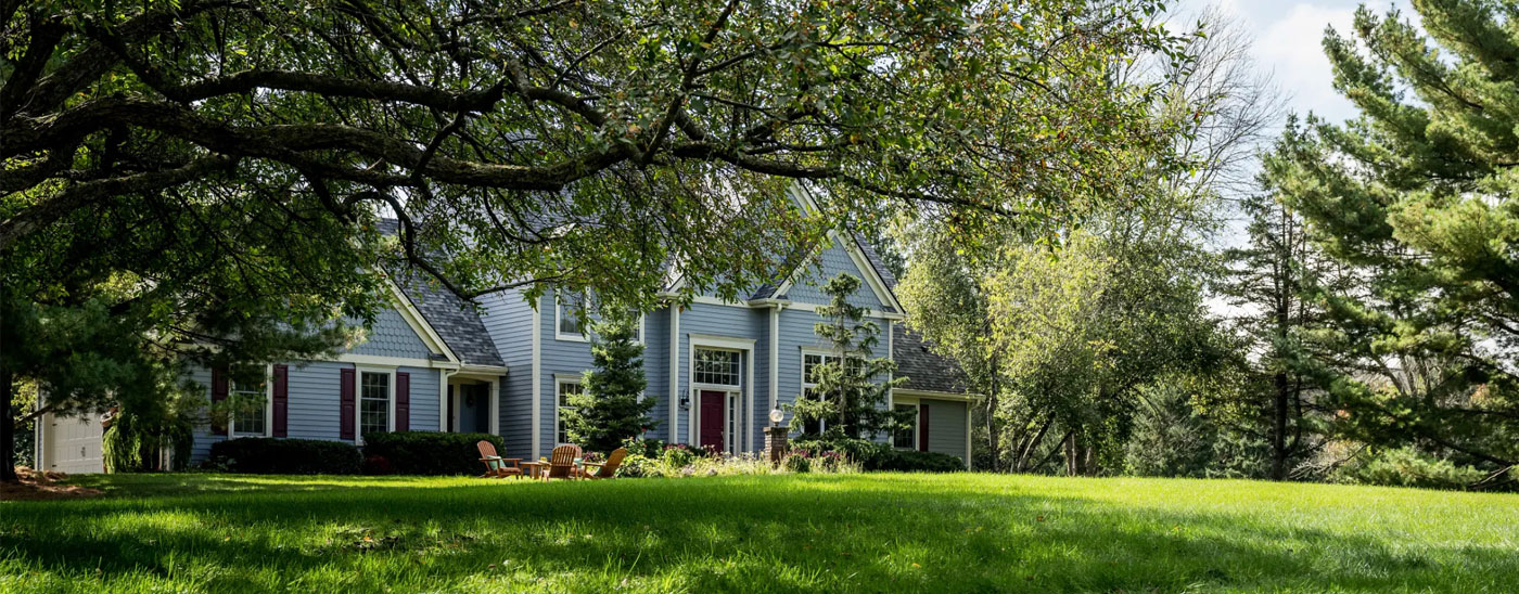 A country home with a large mowed lawn and mature trees