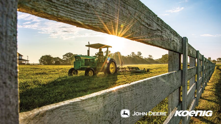 John Deere utility tractor seen past a wooden fence